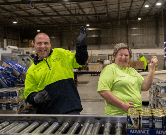 Two people who work at Merriwa are dancing in a warehouse